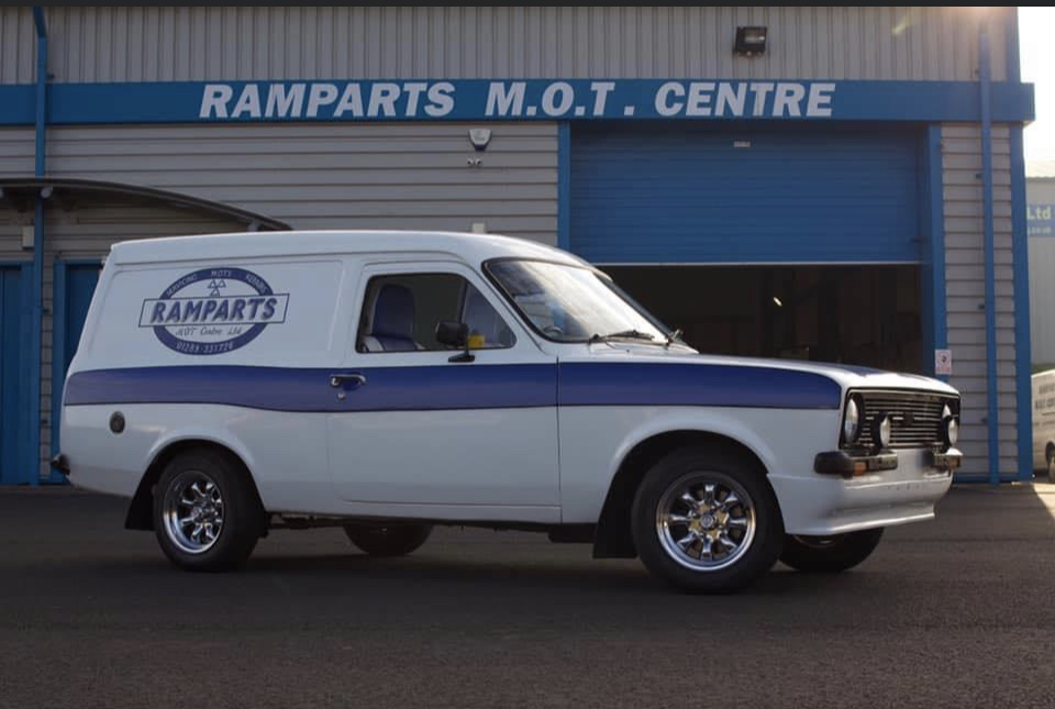 Ramparts' classic Ford Escort van in white with a blue stripe and the RAMPARTS oval badge