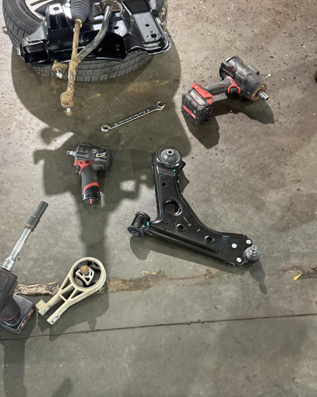 A removed wishbone, engine mount and impact guns on the workshop floor