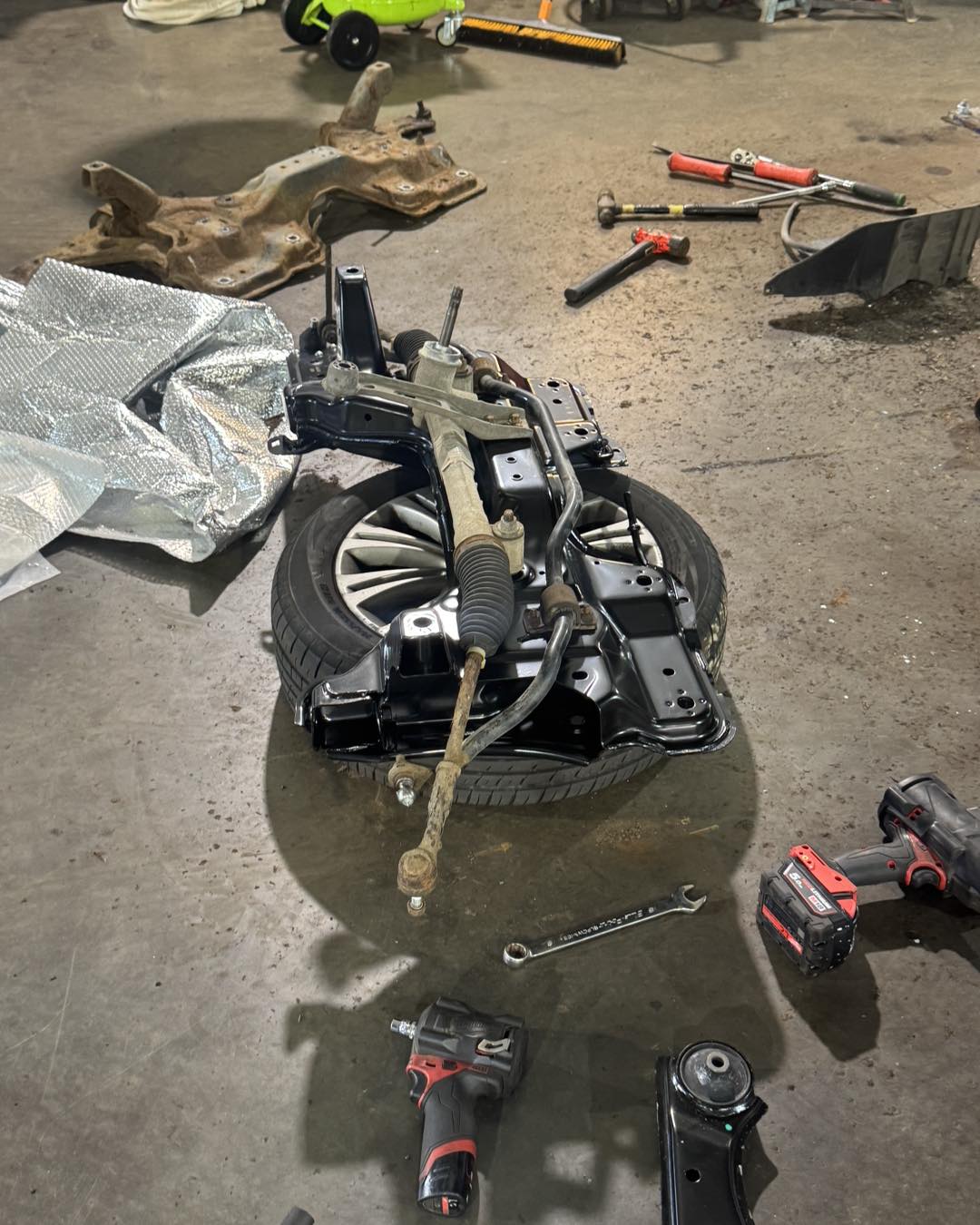 Suspension parts, a subframe and tools laid out on the Ramparts workshop floor